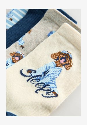 Three pairs of socks: one navy ribbed, one beige with a dog design in blue, and one cream featuring a handwritten "sleepy" text.