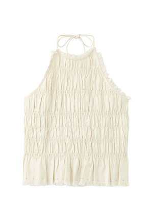 Mladá žena s dlhými tmavými vlasmi, ktorá má na sebe biely bezrukávový nariasený halter top a čierne rifľové šortky s ozdobnými cvokmi.