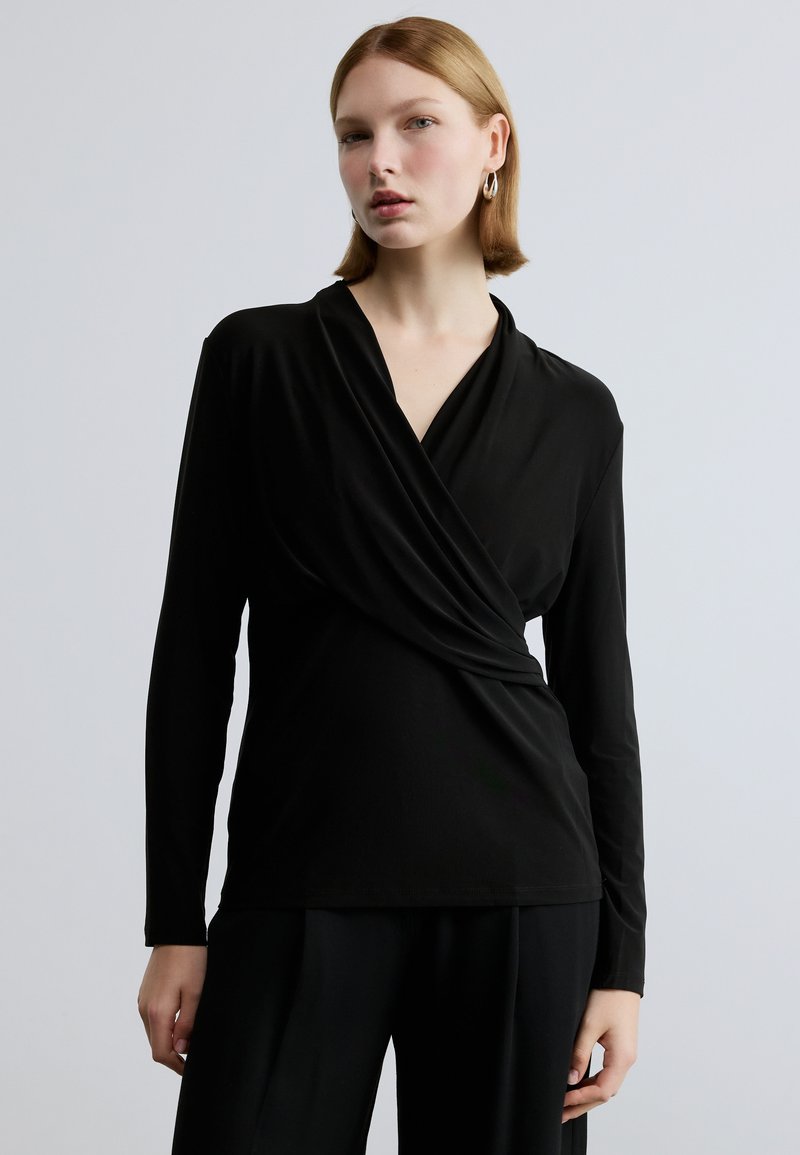 Zwarte blouse met lange mouwen en een overslagontwerp, met een zachte textuur en een V-hals. De stof lijkt glad en aansluitend te zijn.