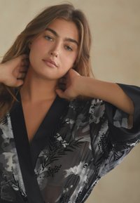 Musthave mustriline mustril V-kaelusega must floral keemone, mis on valmistatud läbipaistvast kangast, featuring erinevaid halli ja valge lillemustreid, laiade varrukatega.