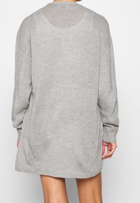 Maglione oversize grigio chiaro con maniche lunghe, orlo a coste e pannelli laterali in maglia aperta. Tessuto morbido e vestibilità rilassata.