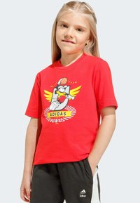 Červené bavlnené tričko s grafikou kresleného charakteru so žltými krídlami a basketbalovou loptou. Krátke rukávy a okrúhly výstrih.
