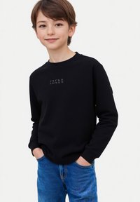 Felpa nera con colletto a girocollo e logo sul petto. Maniche lunghe e polsini a costine. Jeans blu con una leggera texture e dettagli di cucitura.