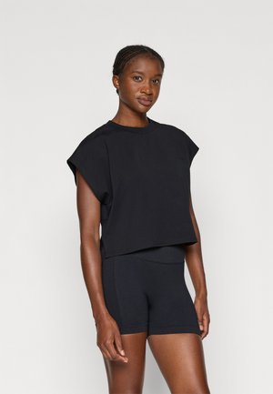 Svart cropped t-skjorte med korte ermer og rund hals, kombinert med svarte treningsshorts med mesh-detaljer i sidene.
