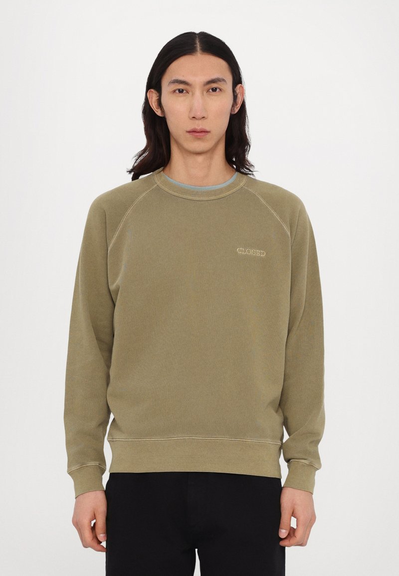 Olivengrøn sweatshirt i blødt materiale, med rund hals og raglanærmer, udstyret med en diskret broderet logo på brystet.