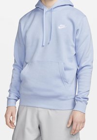 Ljusblå Nike-hoodie i mjukt material, med en framficka, dragsko på huvan och vit logotyp på bröstet.