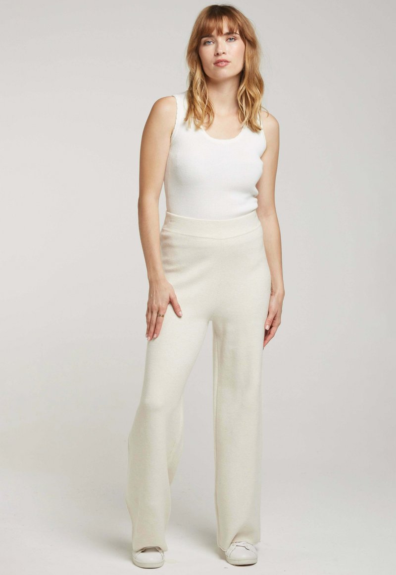 Débardeur côtelé couleur crème associé à un pantalon large à taille haute en tissu doux ; mannequin portant des baskets blanches.