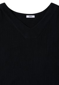 Haut en tissu noir texturé avec un large décolleté en V et une étiquette blanche avec l'inscription "CECIL" cousue à l'intérieur du col.
