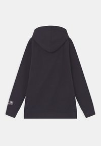 Svart långärmad hoodie med huva och liten vit tryckt etikett på nedre vänstra ärmen, sedd bakifrån.