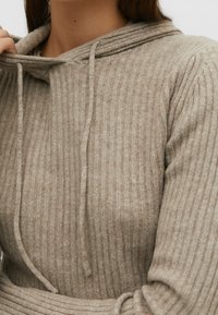 Pull beige côtelé avec capuche à cordon. Texture douce, coupe ajustée et rayures verticales prononcées créent une apparence confortable.