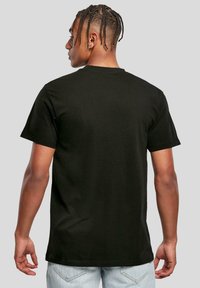 Sort bomulds T-shirt med korte ærmer, rund hals og afslappet pasform. Glat tekstur, ingen synlige mønstre, båret med lyseblå jeans.