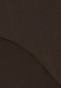 Hnědá látka s hladkou strukturou a jemným žebrováním, s bezproblémovým přechodem mezi dvěma odstíny tmavě hnědé.