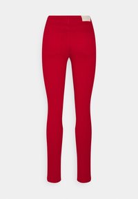 Jeans skinny rojos fabricados con una mezcla de algodón, con bolsillos traseros y una etiqueta discreta en la cintura. Textura suave con un diseño ajustado.