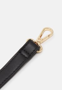 Sort læderrem med en struktureret overflade, der har en guldfarvet metalspænde og ring til fastgørelse. Paneler synlige i nærheden af spændeområdet.