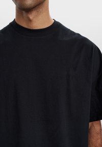 Sort bomuld t-shirt med rund hals, korte ærmer og et struktureret, ensfarvet stof; ingen synlige logoer eller mønstre.