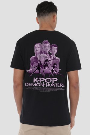 Mann trägt schwarzes T-Shirt mit lila animierten weiblichen Figuren und dem Schriftzug "K-POP DEMON HUNTERS" auf dem Rücken vor einfachem Hintergrund.