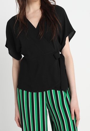 Czarny top kopertowy z krótkimi rękawami, z wiązaniem w talii. W połączeniu z zielono-czarnymi, wysokim stanem, pasiastymi spodniami. Gładka faktura materiału.