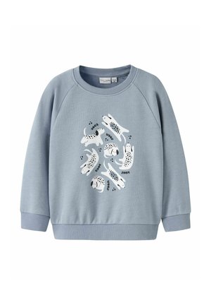 Hellblaues Sweatshirt mit rundem Ausschnitt und gerippten Bündchen. Es zeigt ein verspieltes Design mit weißen Hunden mit schwarzen Flecken sowie dem Text "HUNDE" und "WUFF".