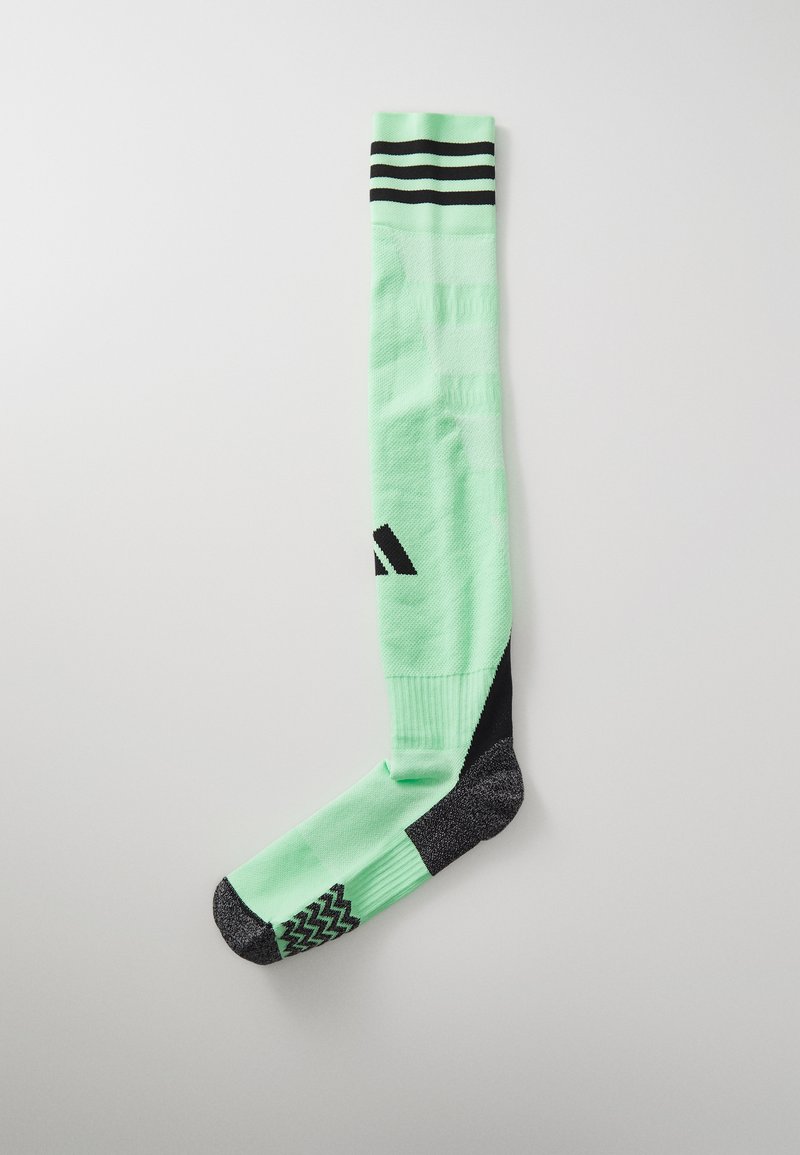 Meia de desporto verde com punho listrado em preto, apresentando uma textura padrão na parte do pé. O design é até ao joelho com detalhes em preto contrastantes.