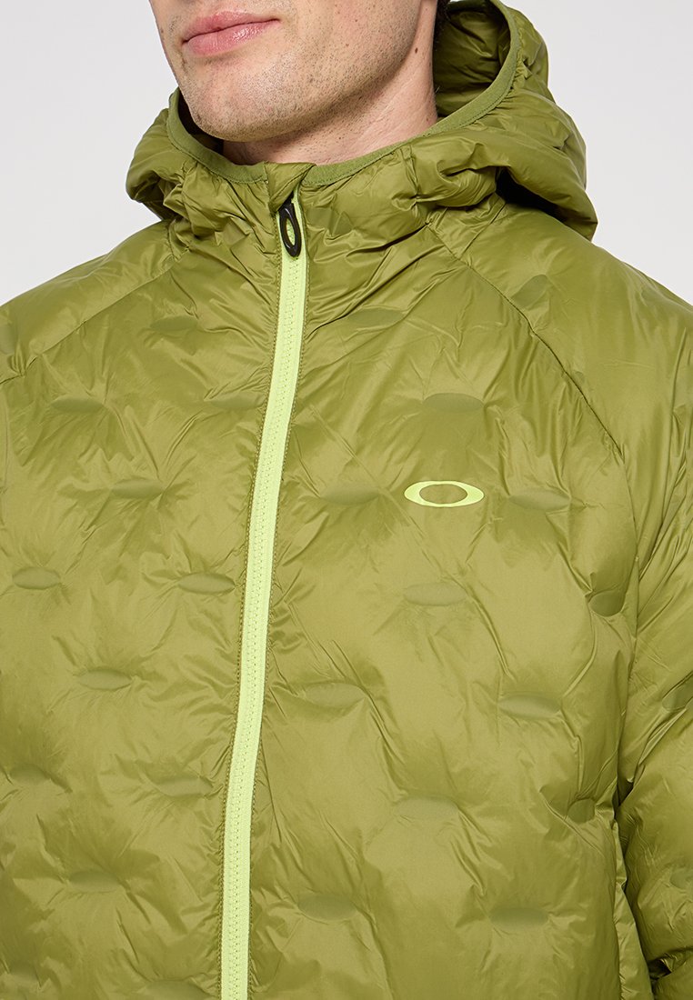 Chaqueta inflable verde con un patrón texturizado y acolchado. Presenta un cierre completo con una cremallera de un tono verde claro contrastante y una capucha ajustable.