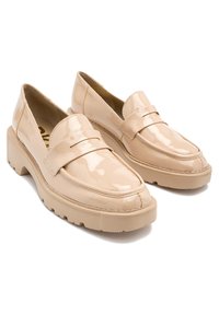 Beżowe lakierowane loafersy z grubą podeszwą, zaokrąglonym czubkiem i akcentem w postaci paska. Gładka, błyszcząca faktura z subtelnymi detalami przeszyć.
