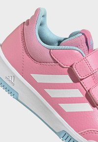 Zapatilla deportiva rosa con parte superior de cuero texturizado, lengüeta de malla, rayas blancas y detalles azules en el forro y la suela. Cierre de velcro.