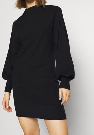 Abito nero oversize con maniche lunghe e puffate e polsini a costine. Il tessuto morbido e l'orlo inferiore aderente creano una silhouette rilassata.