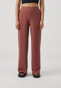 Weite, gerippte Hosen in staubigem Rosé mit hohem Bund und weichem Material. Kombiniert mit schwarzen Plateausandalen.