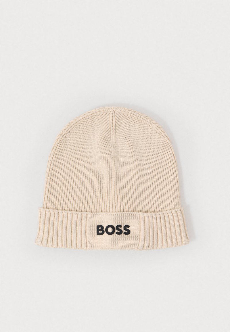Bonnet en tricot beige avec un fond côtelé et un logo "BOSS" noir à l'avant. Texture douce et design ajusté.