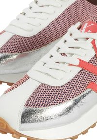 Des chaussures de sport avec une tige en mesh rose, des accents blancs, un capuchon métallique argenté et une semelle en caoutchouc avec un motif de grip visible.