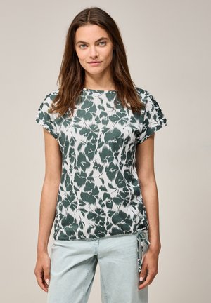 Haut à manches courtes vert et blanc à motif, en tissu doux, avec un col rond, détails froncés sur les manches et un lien ajustable à la taille.
