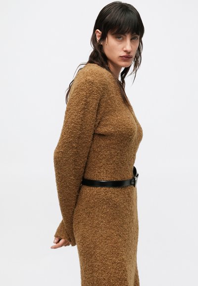 Bruine, gestructureerde gebreide jurk met lange mouwen, voorzien van een zwarte riem in de taille. Gladde, zachte stof met een comfortabele pasvorm.