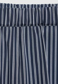 Námořnická modrá látka s bílými svislými pruhy. Obsahuje nařasený pas a plisovanou strukturu pro flexibilitu a pohodlí.