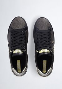 Sneaker neri con una tomaia testurizzata caratterizzata da un motivo geometrico, lacci neri, dettagli dorati sulla linguetta e una suola metallica.