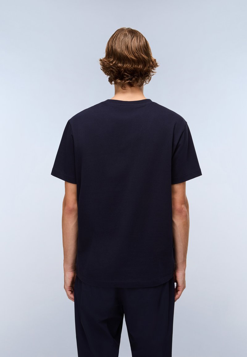 Maglietta in cotone blu navy con scollo rotondo, maniche corte e vestibilità rilassata, vista dal retro. Texture liscia e design semplice.