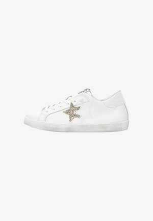 Sneaker bianca a bassa top con lacci bianchi, decorazioni di stelle glitterate oro e bianche sui lati e suola leggermente usurata.