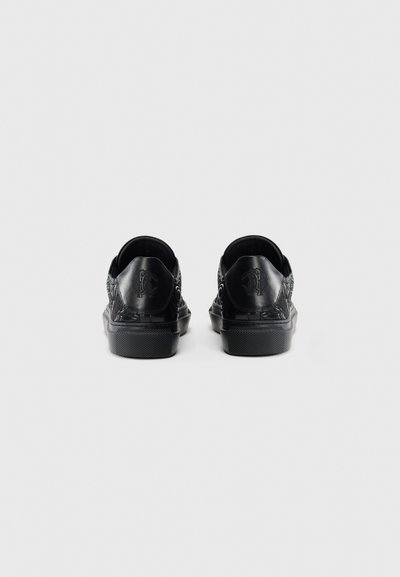 Zapatillas negras con parte superior de cuero texturizado, punta redondeada y suela de goma de perfil bajo. Presenta un acento de logotipo en el talón y un detallado intrincado.