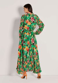 Florales Wickelkleid mit lebhaft grünem Hintergrund, orangefarbenen und pinken Blumen, langen Ärmeln und gebundener Taille, mit einem fließenden Rock.