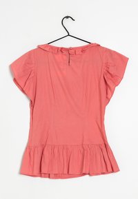 Blusa corallo corta con maniche a sbuffo, orlo svasato e apertura a chiave sul retro. Realizzata in tessuto leggero.