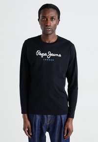 Camiseta negra de manga larga hecha de algodón, con un logotipo en letra blanca "Pepe Jeans" y "LONDON" en azul debajo del logotipo.