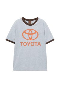 Šedé bavlnené tričko s hnedým rebrovaným golierom a akcentmi na rukávoch. Na prednej strane sa nachádza oranžové logo Toyota a stredne umiestnený text.