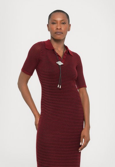 Ribbed knit dress in dark red and black stripes with a collared neckline and short sleeves. Features a decorative bolo tie accent.