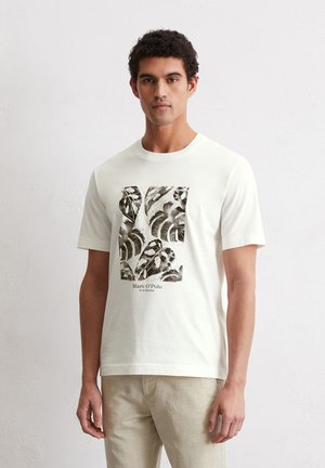 Cream-colored short-sleeve t-shirt features a black and white leaf-pattern graphic on the front with "Marc O'Polo" text beneath.