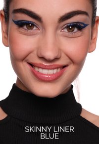 Eyeliner blu con punta sottile crea un audace design a ala sulla palpebra superiore. La modella sorride, indossando una maglia nera a collo alto.