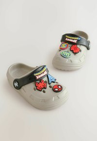 Hellgraue Kunststoff-Clogs mit einem schwarzen Riemen, verziert mit bunten Superhelden-Motiven, darunter ein Spinnen- und ein Netzdesign.