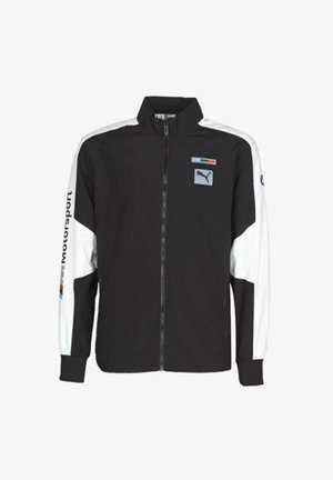 Veste de sport en noir et blanc avec zip frontal intégral, col haut, poches latérales et logo Puma sur la poitrine et la manche.