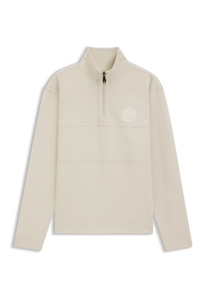 Light beige zip-up pullover featuring a high collar, long sleeves, and a textured fabric with a circular logo accent on the chest.