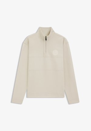 Vaaleanbeige vetoketjullinen pusero, jossa on korkea kaulus, pitkät hihat ja teksturoitu kangas, jonka rinnassa on pyöreä logo.