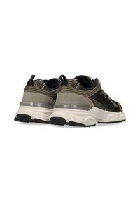 Texturerade sneakers i mörk olivgrön och svart mesh, med en kraftig vit mellansula och en genomskinlig yttersula; bakifrån framhävs snörningen och detaljerna.