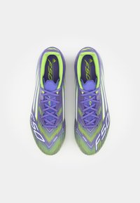 Purple and green soccer cleats feature a textured upper, angled stripes, and prominent "F50" branding. Lightweight design with laces.